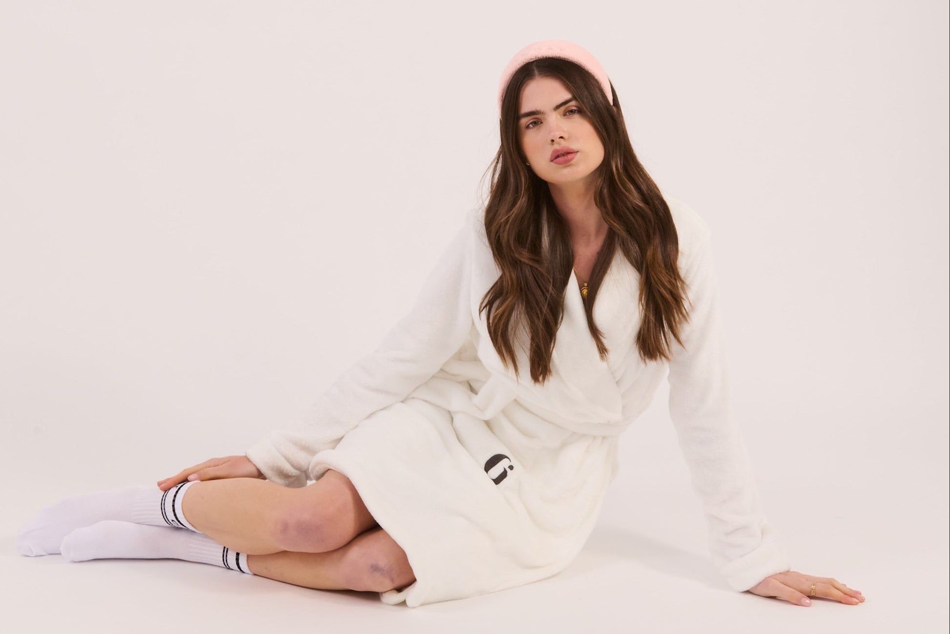Woman wearing a white robe with a brand logo on a plain background
